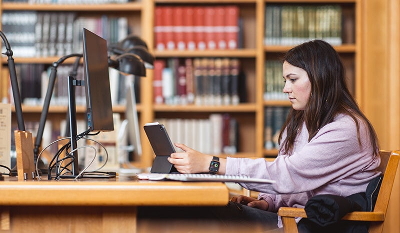 Student studying in the Lane Reading Room inside Green Library. 